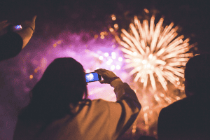 Woman taking a picture of a fireworks display.