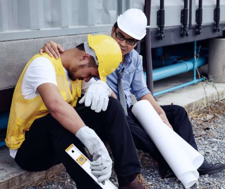an engineer comforts a sad construction worker